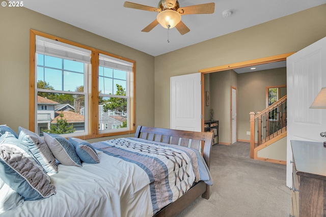 bedroom with baseboards, multiple windows, light carpet, and a ceiling fan