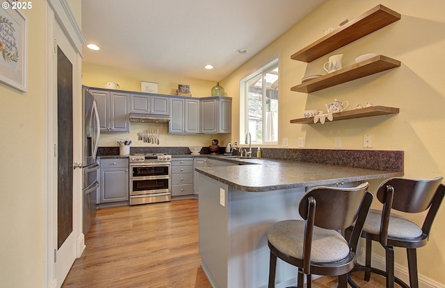 688 53rd St, Washougal, WA 98671 - kitchen with stainless steel appliances, gray cabinetry, a peninsula, dark countertops, and under cabinet range hood