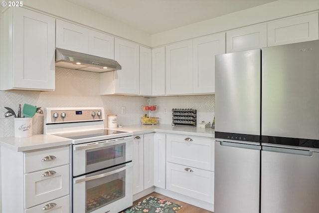 718 Rhoades Rd, Winlock, WA 98596 - kitchen featuring under cabinet range hood, double oven range, freestanding refrigerator, white cabinetry, and light countertops