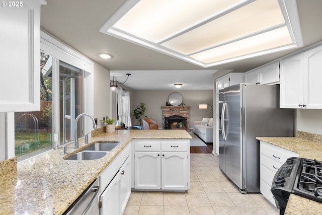 15421 SW Thurston Ln, Portland, OR 97224 - kitchen featuring a sink, appliances with stainless steel finishes, light tile patterned flooring, white cabinets, and a fireplace