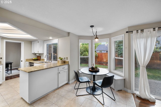 15421 SW Thurston Ln, Portland, OR 97224 - kitchen with a sink, light stone countertops, a peninsula, baseboards, and a textured ceiling