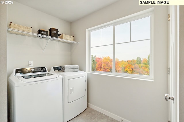 washroom featuring washer and clothes dryer, plenty of natural light, baseboards, and light tile patterned floors
