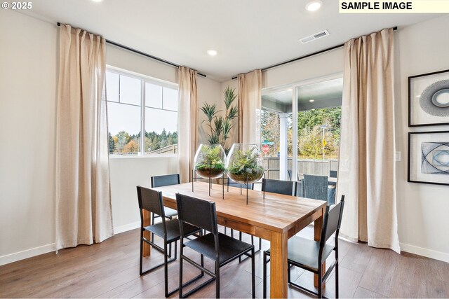 dining space with baseboards, wood finished floors, and recessed lighting