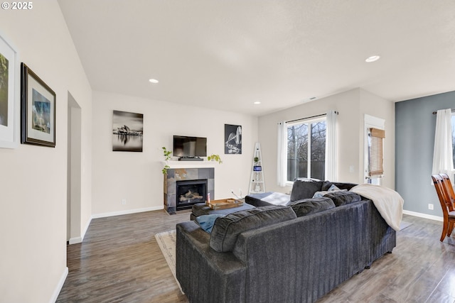 living area featuring recessed lighting, a fireplace, baseboards, and wood finished floors