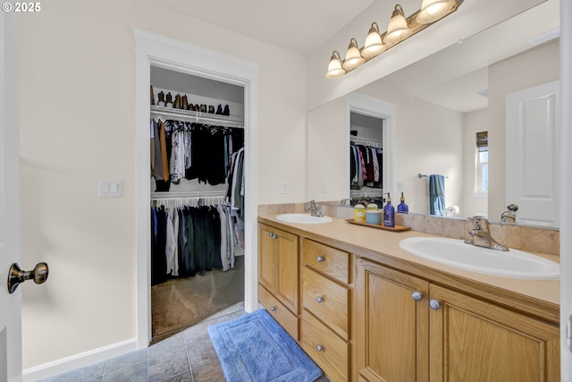 full bath with double vanity, a sink, a spacious closet, and tile patterned floors