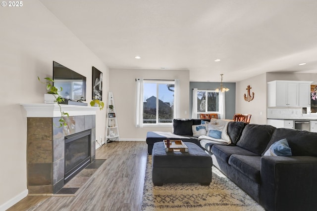 living room featuring an inviting chandelier, a fireplace, baseboards, and wood finished floors