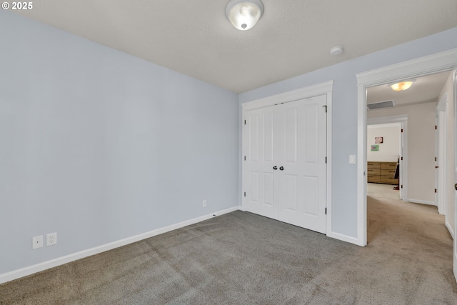 unfurnished bedroom with carpet floors, a closet, visible vents, and baseboards