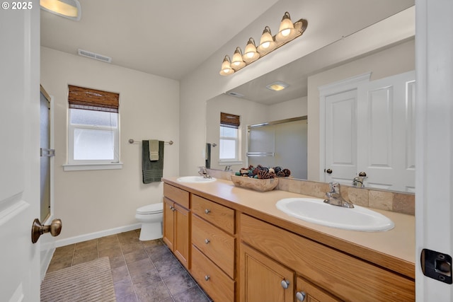 bathroom with double vanity, an enclosed shower, toilet, and a sink