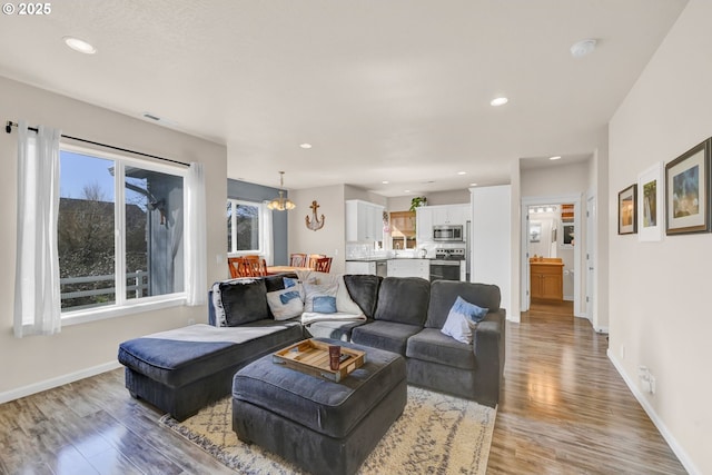 living area with recessed lighting, visible vents, light wood-style flooring, a chandelier, and baseboards