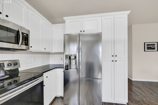 kitchen featuring stainless steel appliances, dark countertops, and white cabinetry