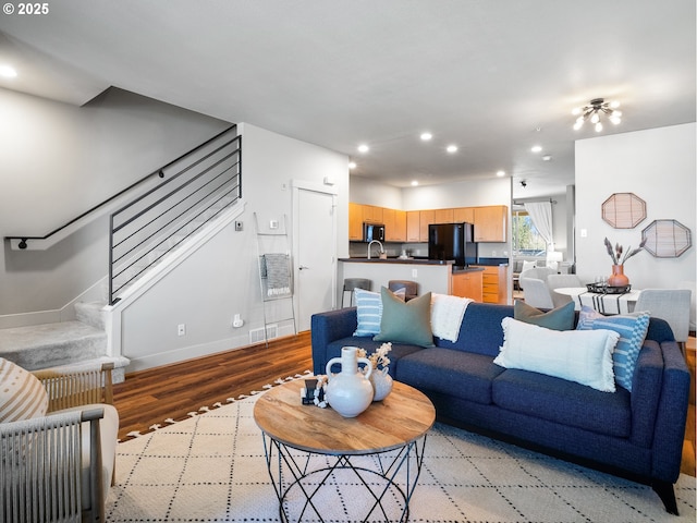 living area featuring light wood finished floors, stairs, baseboards, and recessed lighting