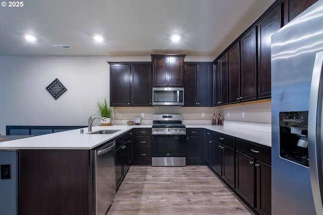 kitchen with dark brown cabinetry, stainless steel appliances, sink, and light wood-type flooring