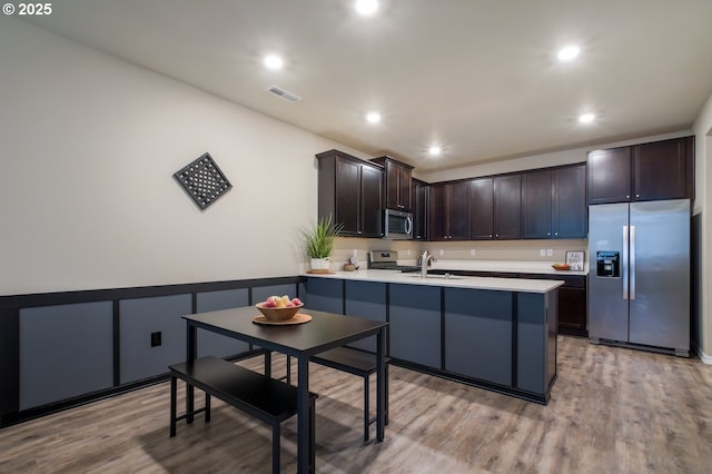 kitchen featuring appliances with stainless steel finishes, sink, dark brown cabinets, and light hardwood / wood-style flooring