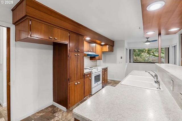 kitchen featuring a sink, light countertops, brown cabinetry, electric stove, and under cabinet range hood