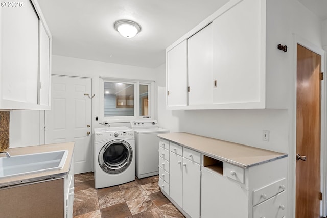 laundry room featuring cabinet space, separate washer and dryer, stone finish floor, and a sink