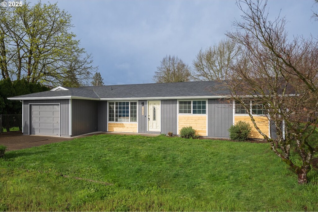 single story home featuring a front yard, driveway, an attached garage, and fence