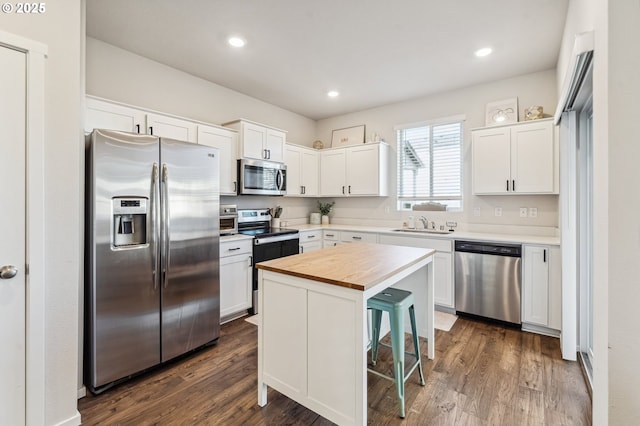 kitchen featuring appliances with stainless steel finishes, butcher block countertops, dark wood-style floors, and white cabinetry