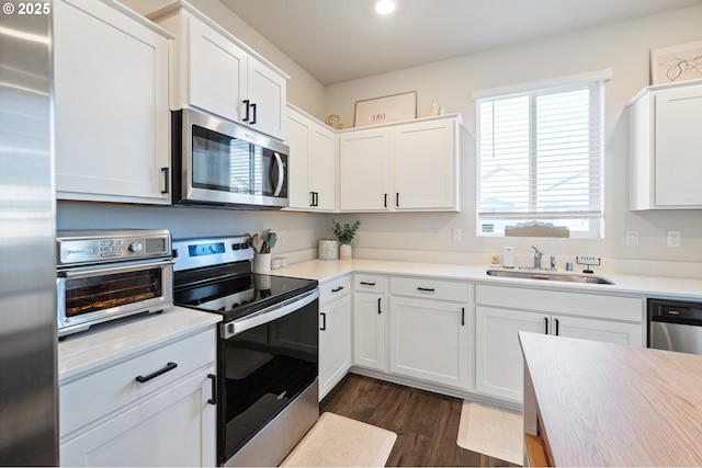 kitchen featuring a toaster, white cabinetry, stainless steel appliances, and a sink