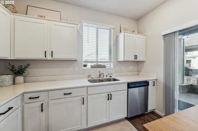 kitchen with dark wood-style flooring, a sink, white cabinetry, light countertops, and stainless steel dishwasher