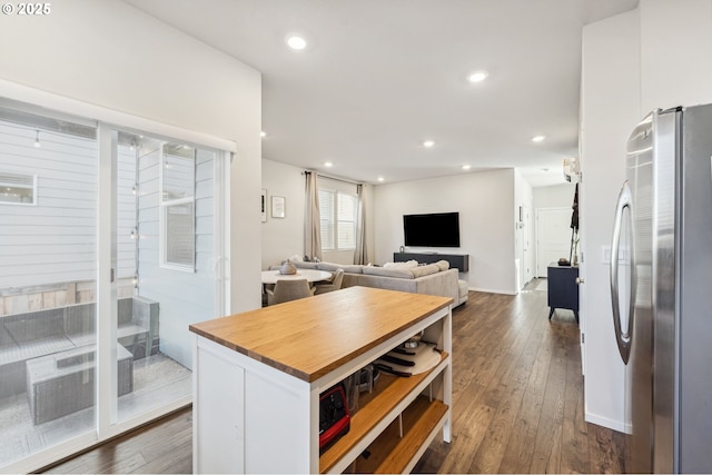 kitchen with dark wood-style floors, wooden counters, freestanding refrigerator, and white cabinetry