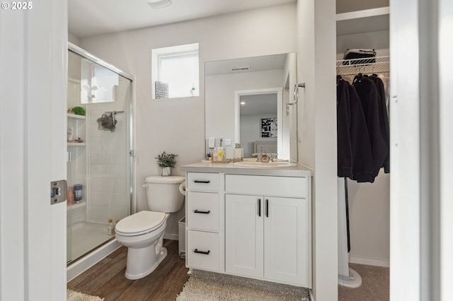 full bathroom with toilet, a stall shower, visible vents, and wood finished floors
