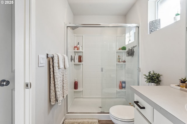 bathroom with a stall shower, vanity, and toilet