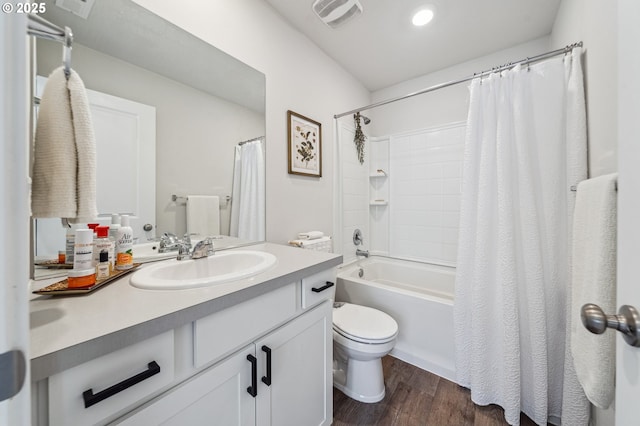 bathroom with toilet, wood finished floors, vanity, visible vents, and shower / bath combo