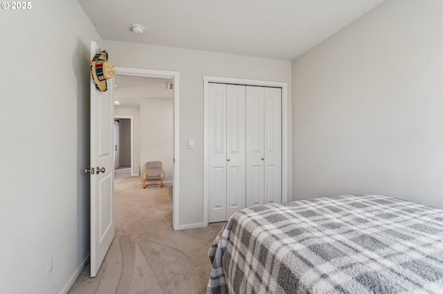 bedroom featuring baseboards, a closet, and light colored carpet