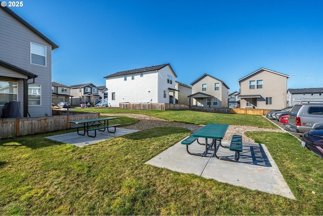 view of community featuring a yard, a residential view, fence, and a patio
