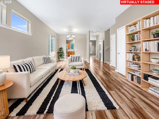 living room with wood-type flooring, a wealth of natural light, and a notable chandelier