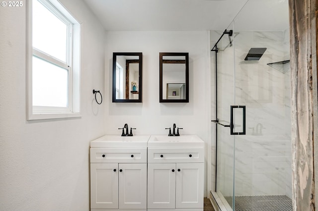 bathroom featuring a sink, a marble finish shower, and double vanity