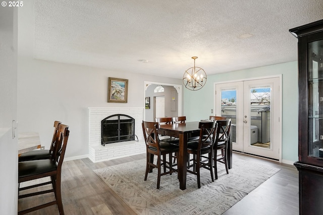 dining room with a fireplace, baseboards, french doors, and wood finished floors