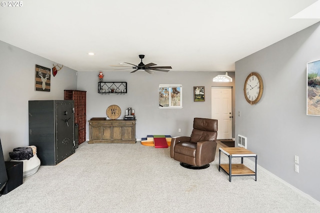 living area featuring visible vents, baseboards, carpet, and ceiling fan