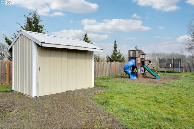 view of shed featuring a trampoline, a fenced backyard, and a playground