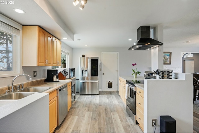 kitchen with a sink, recessed lighting, appliances with stainless steel finishes, wall chimney exhaust hood, and light wood finished floors