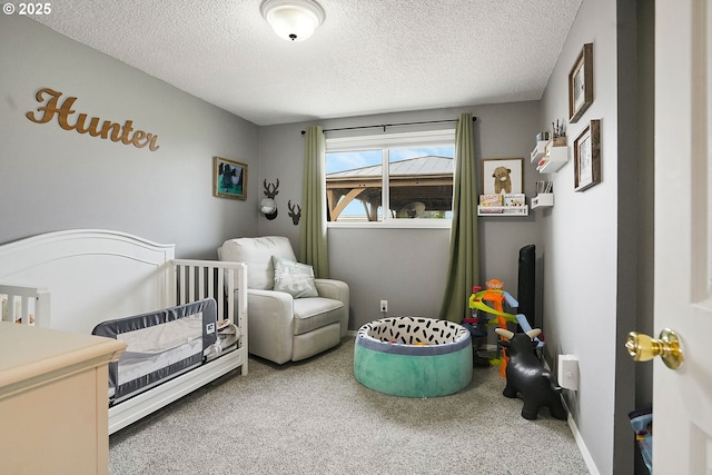 bedroom with baseboards, a crib, carpet, and a textured ceiling