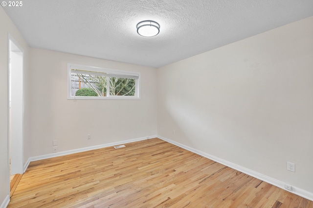 empty room featuring light wood-style floors, visible vents, and baseboards