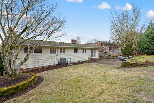 rear view of house featuring entry steps, central AC unit, a lawn, a patio, and a chimney