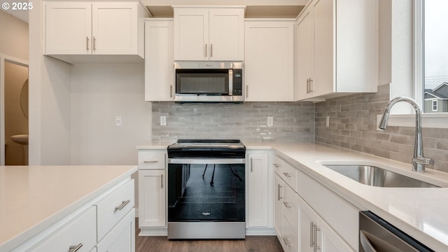 kitchen featuring a sink, stainless steel appliances, light countertops, and white cabinetry