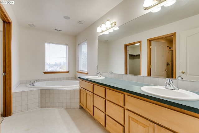 bathroom featuring tiled bath, tile patterned floors, and vanity