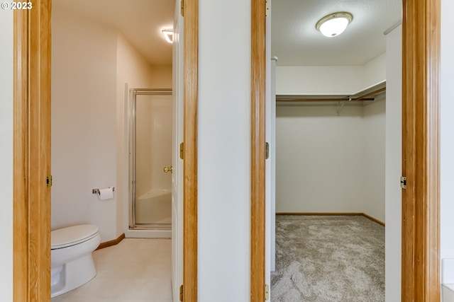 bathroom with a shower with shower door and toilet