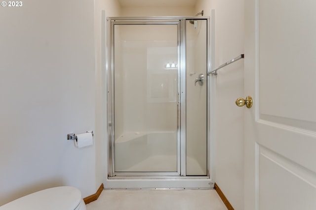 bathroom featuring toilet, tile patterned floors, and a shower with shower door