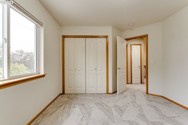 unfurnished bedroom with light colored carpet, multiple windows, and a closet