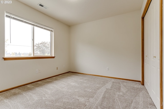 unfurnished bedroom featuring light colored carpet and a closet