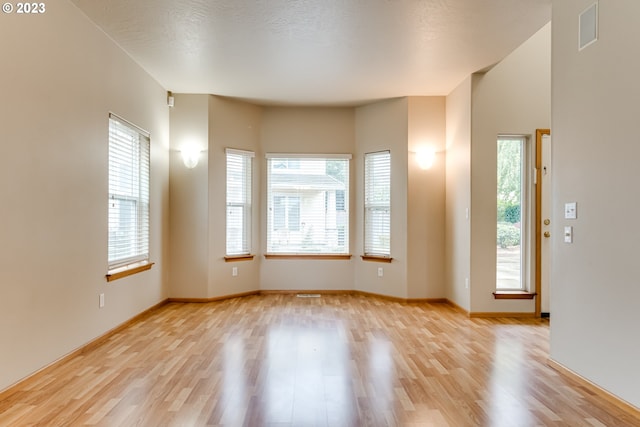 empty room featuring light wood-type flooring and a textured ceiling