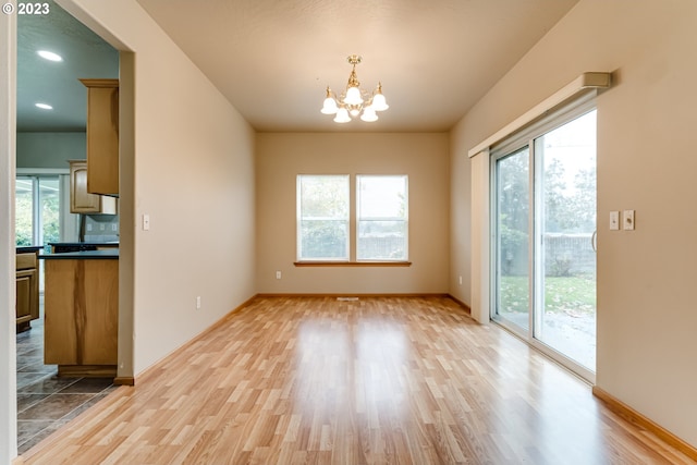 unfurnished dining area with light wood-type flooring and a chandelier