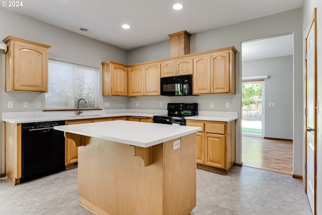 kitchen featuring a center island, black appliances, sink, a kitchen breakfast bar, and light brown cabinetry