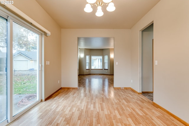 unfurnished room featuring plenty of natural light, light hardwood / wood-style flooring, and a notable chandelier