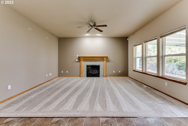 unfurnished living room featuring ceiling fan and a tiled fireplace