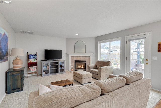 carpeted living area with baseboards, visible vents, recessed lighting, and a tile fireplace